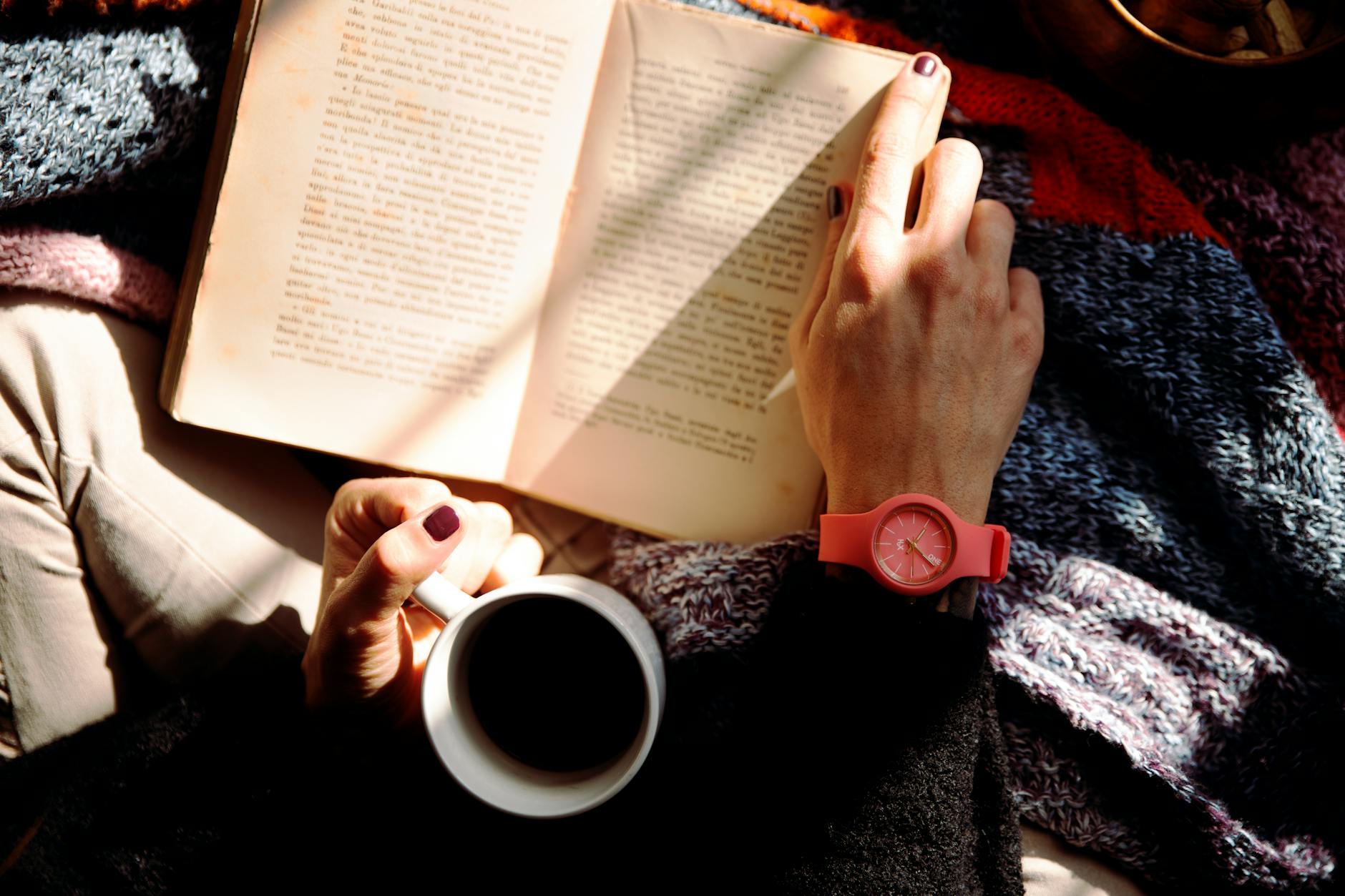 person reading book and holding coffee